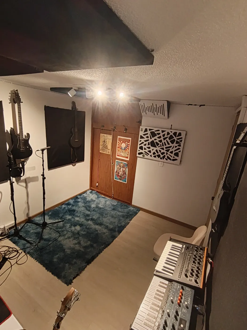 Estudio Clancy: zona de captura con micrófonos en pedestal, guitarras colgadas y difusores acústicos
